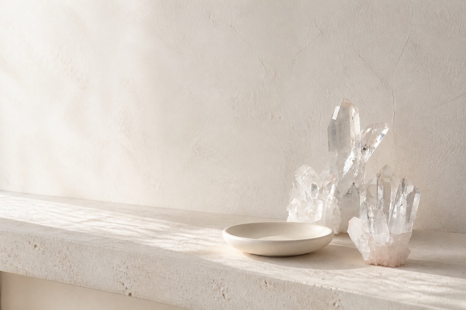 White stone shelf with clear quartz and an empty ceramic dish arranged with generous blank space