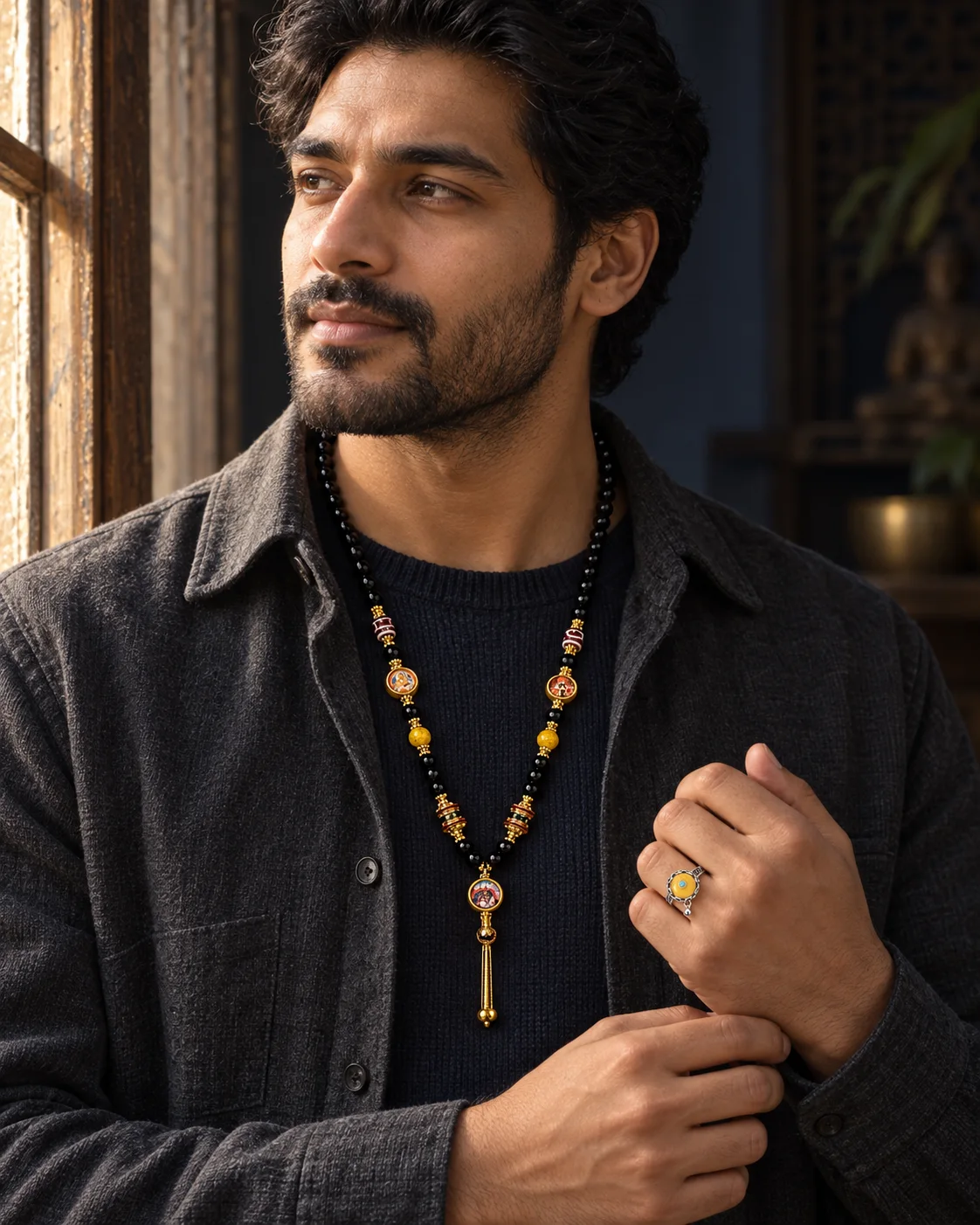 Man wearing a dark beaded pendant and statement ring