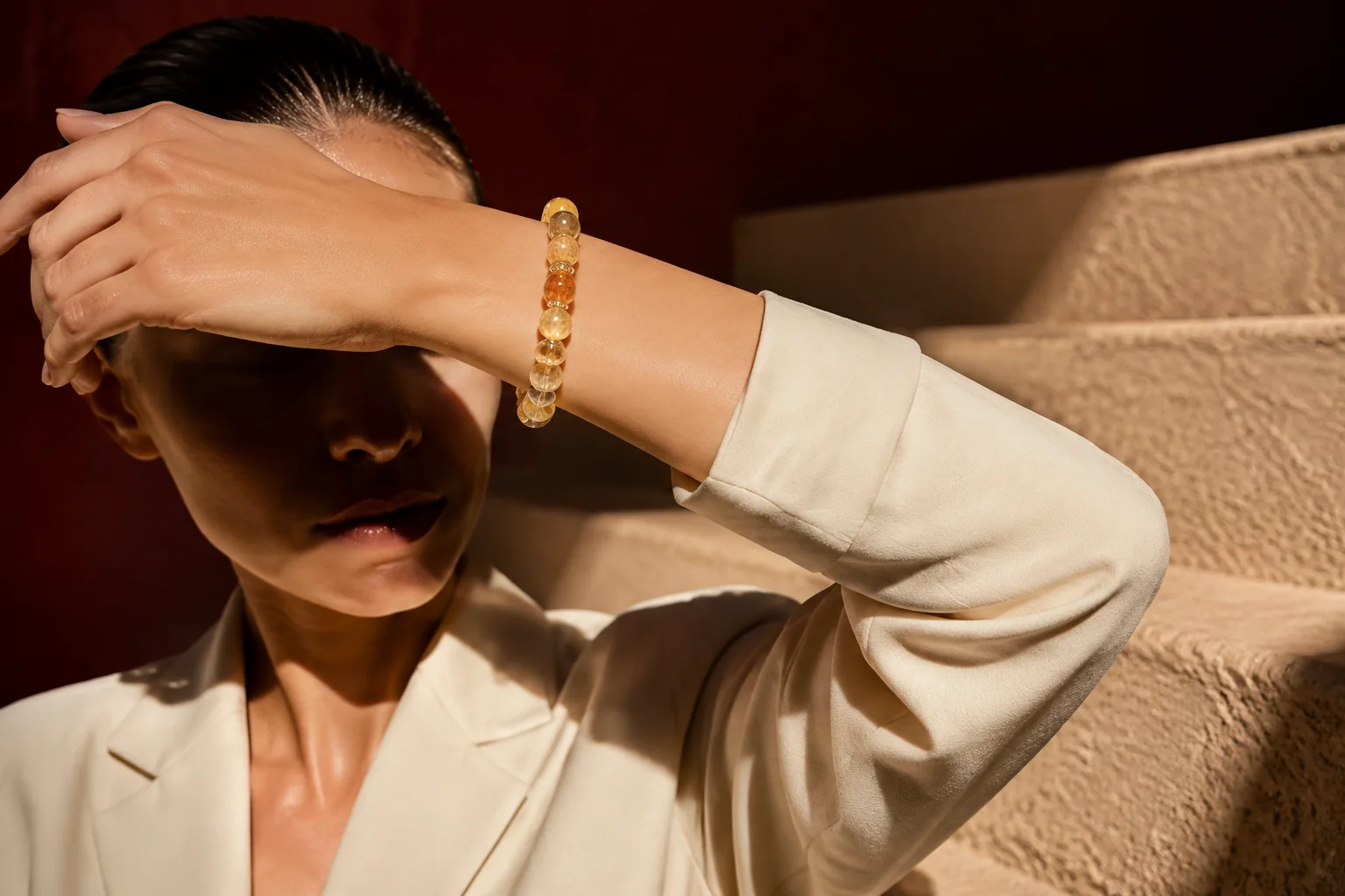 Model wearing a golden citrine amber and tiger eye bracelet in a dramatic sunbeam