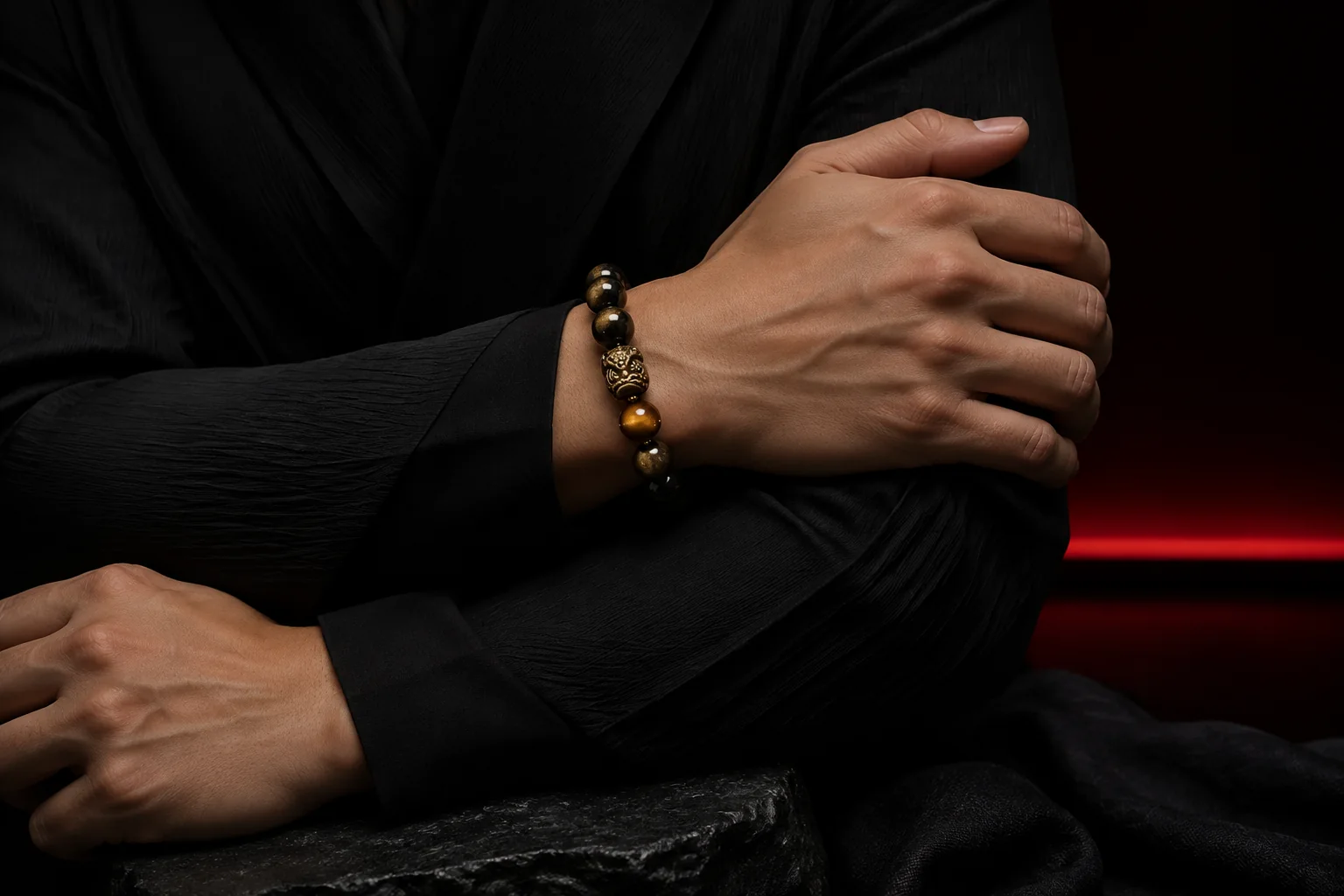 Model wearing a dark tiger eye and obsidian guardian bracelet in a sculptural crossed-arm pose