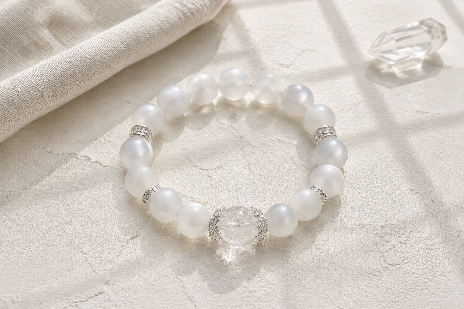 Single moonstone and clear quartz bracelet photographed on an ivory surface